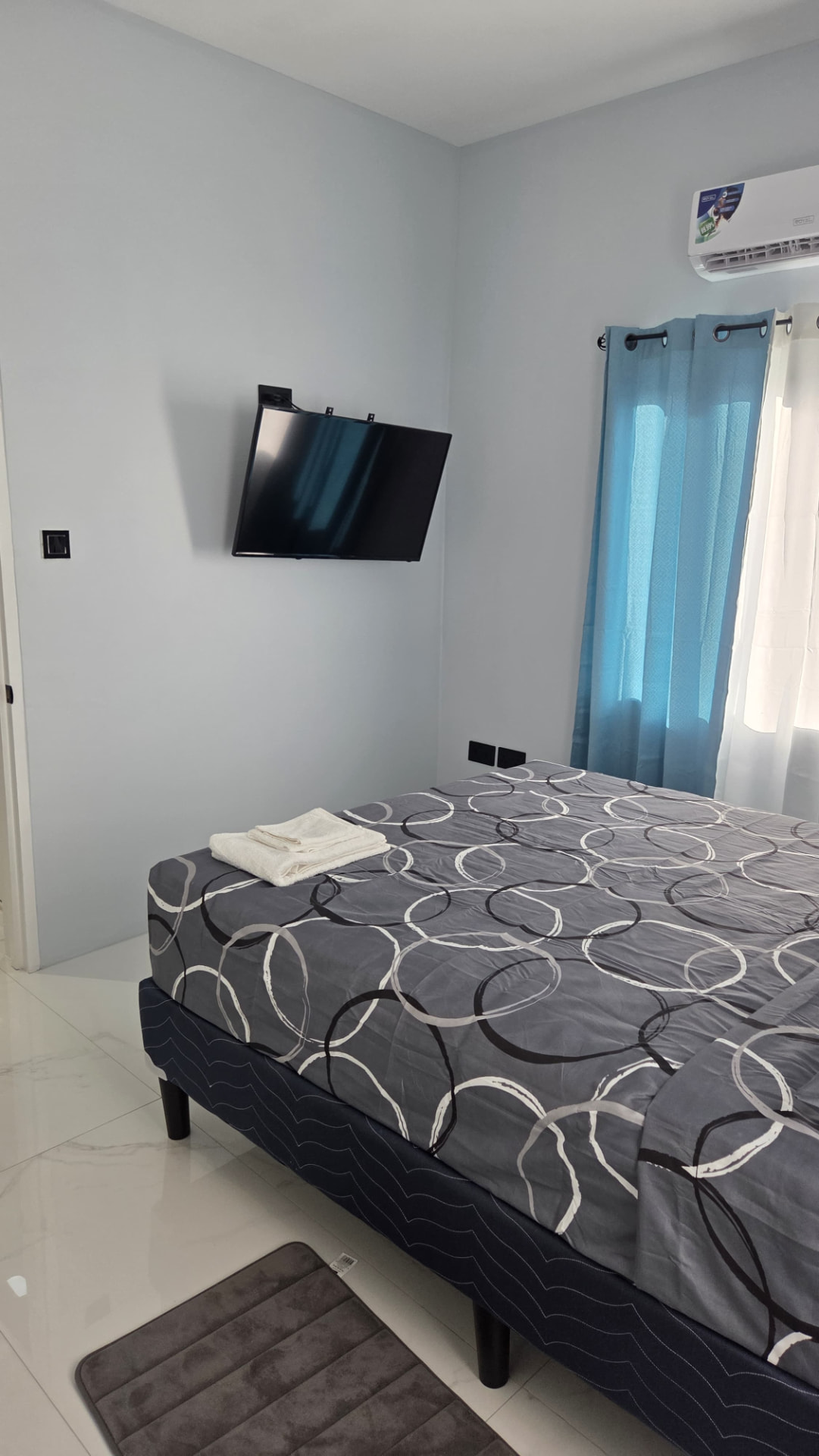 Bright bedroom with wall-mounted smart TV and split-unit air conditioning
